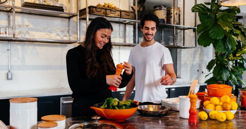 Two happy people preparing food in a spacious kitchen.