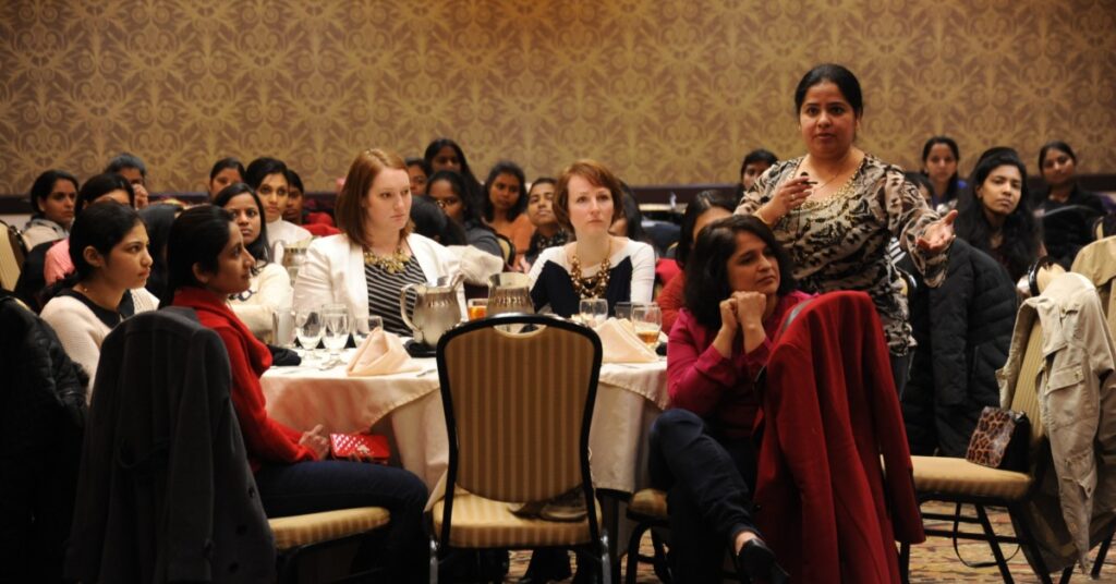 Group of people sitting at tables at a business conference.